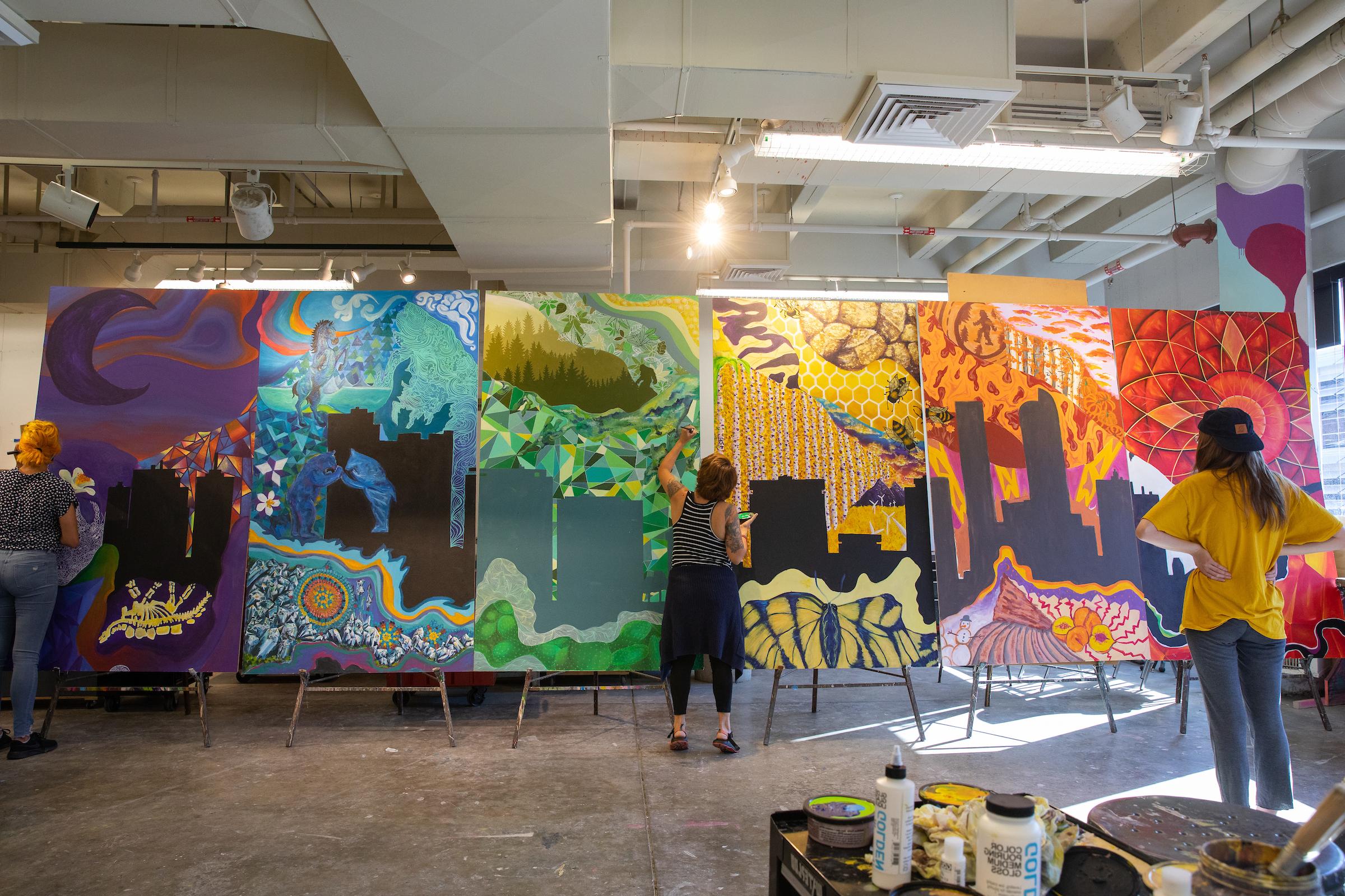 3 students painting a multicolored mural