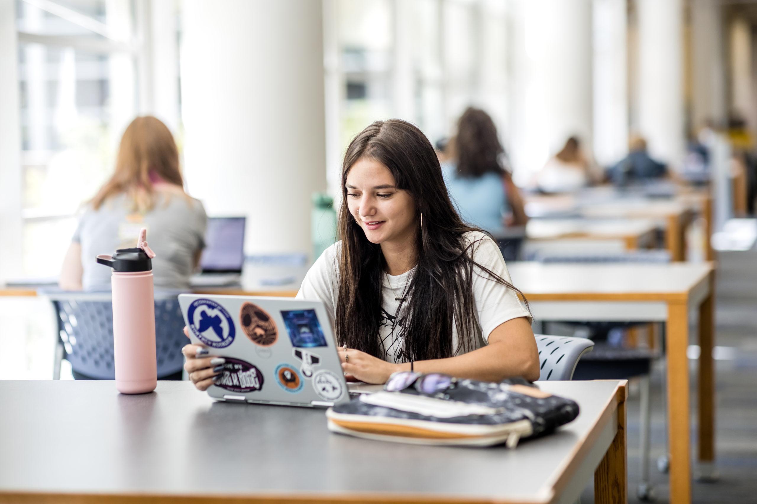 A student sitting on a table working on a laptop